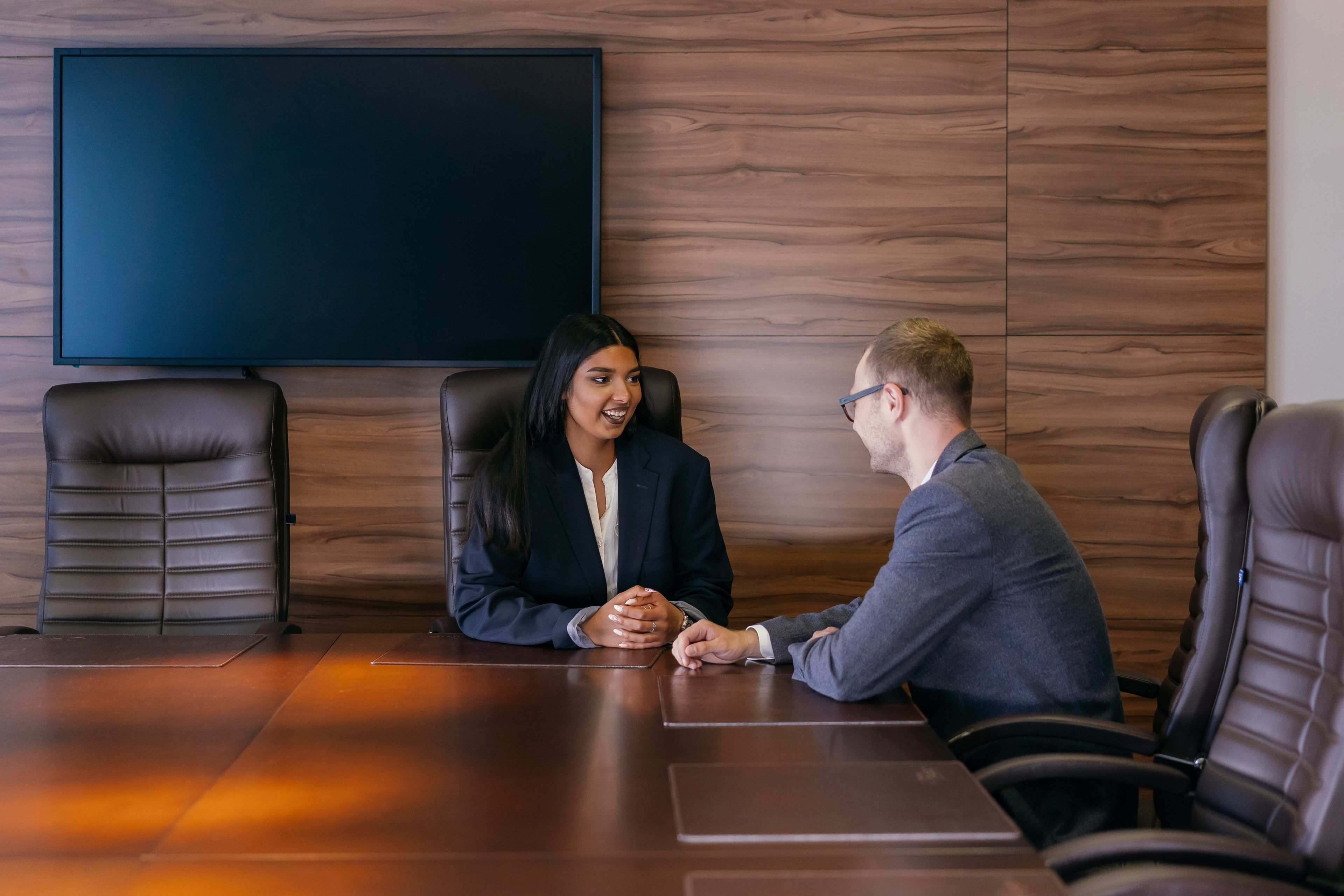 Job candidate smiling and answering a question from an interviewer across a meeting table
