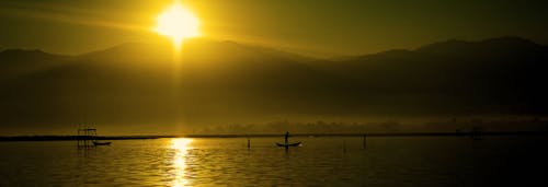 Силуэт людей, катающихся на лодках на воде в дневное время