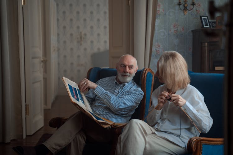 Elderly Couple Sitting And Reading Newspaper