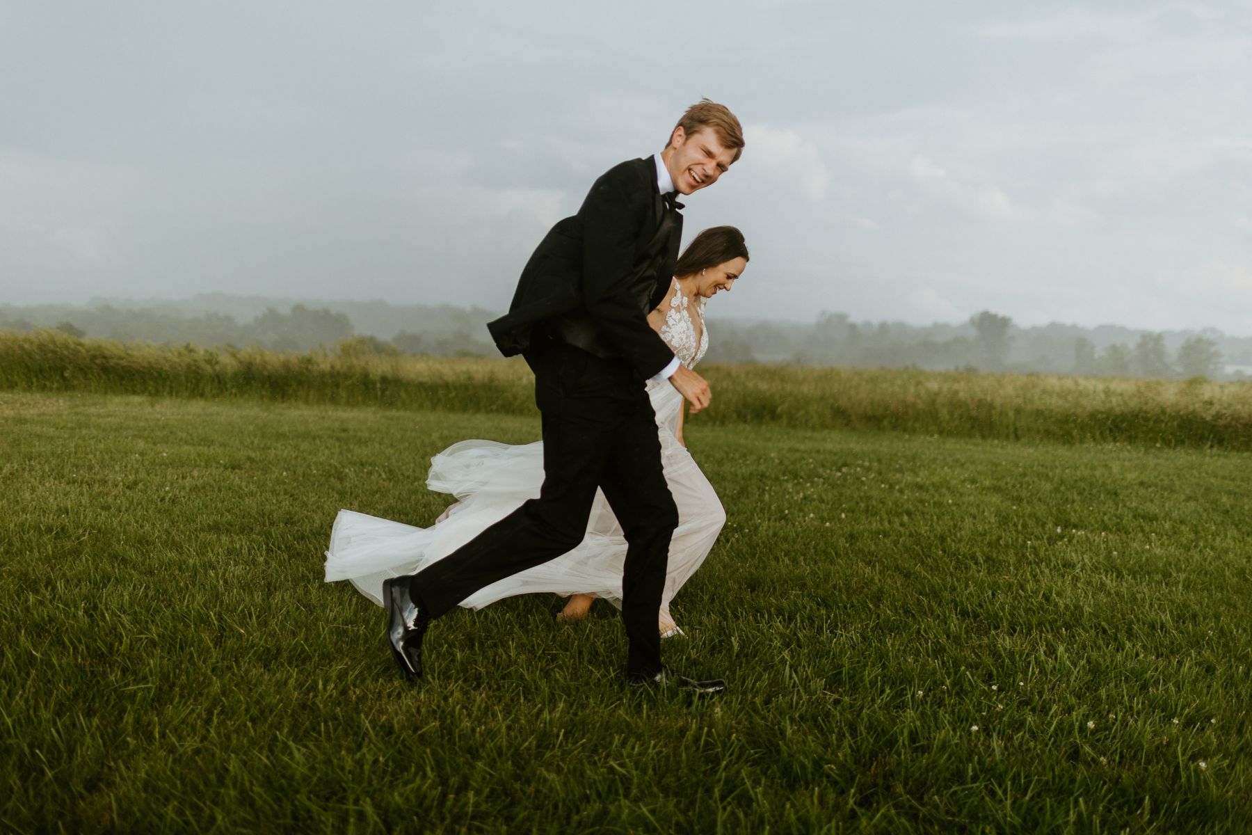 Newlyweds running across a field