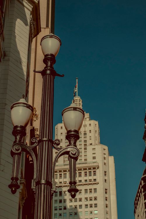 Free Vertical shot of old street lamps with a view of historic buildings and skyline in São Paulo, Brazil. Stock Photo