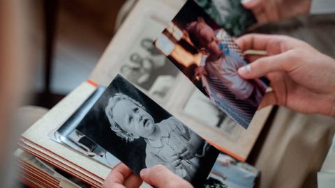 Close-up of hands examining nostalgic family photos in an album.