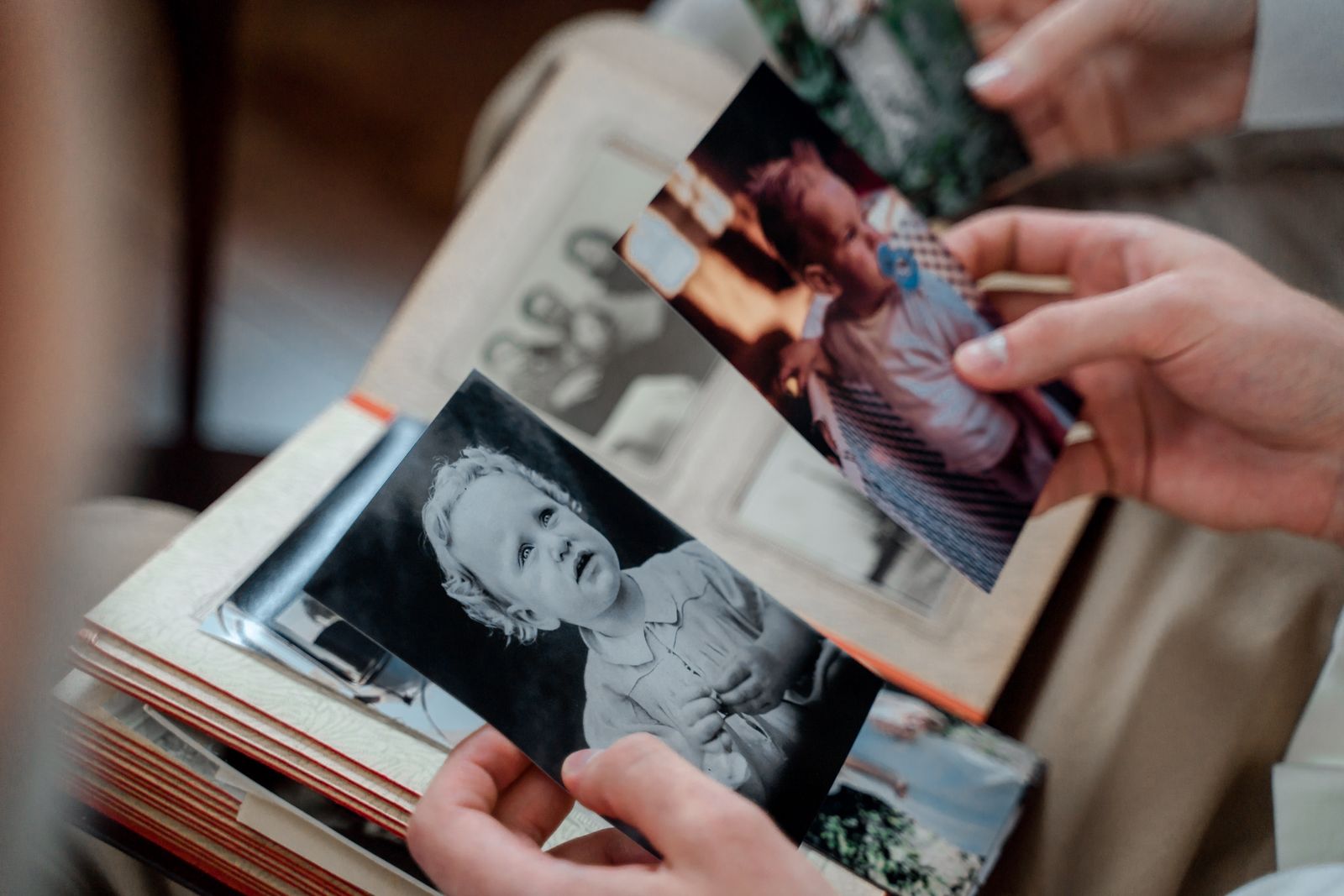 Hands holding old family photographs over an open album