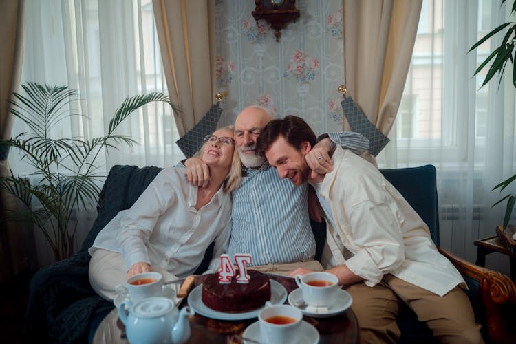 An Elderly Man Hugging His Wife And His Son