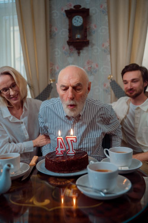 Free An Elderly Man Blowing Candles on His Birthday Cake Stock Photo