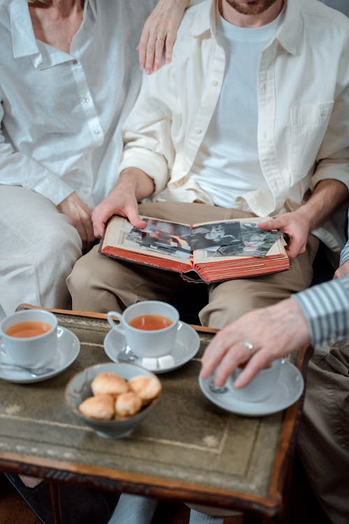 Three People Having Tea Time While Looking At Old Photos