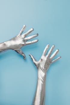 Conceptual shot of hands in silver gloves against a blue backdrop.
