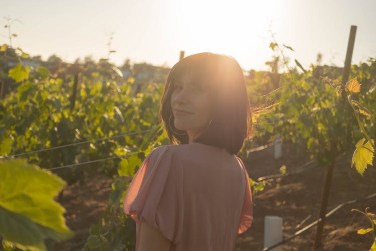 A Woman In A Vineyard Looking Over Her Shoulder