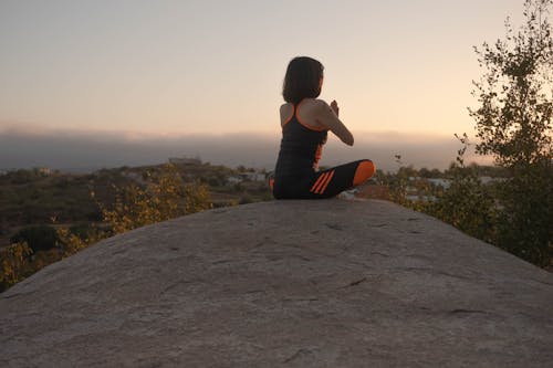 Free A Woman Meditating on Top of a Rock Stock Photo
