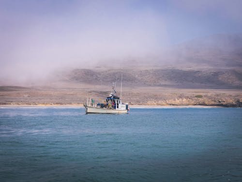 A Fishing Vessel Near a Fog Covered Land