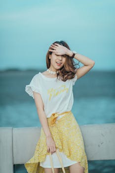 Fashionable young woman in a relaxed pose by the ocean during a sunny day.