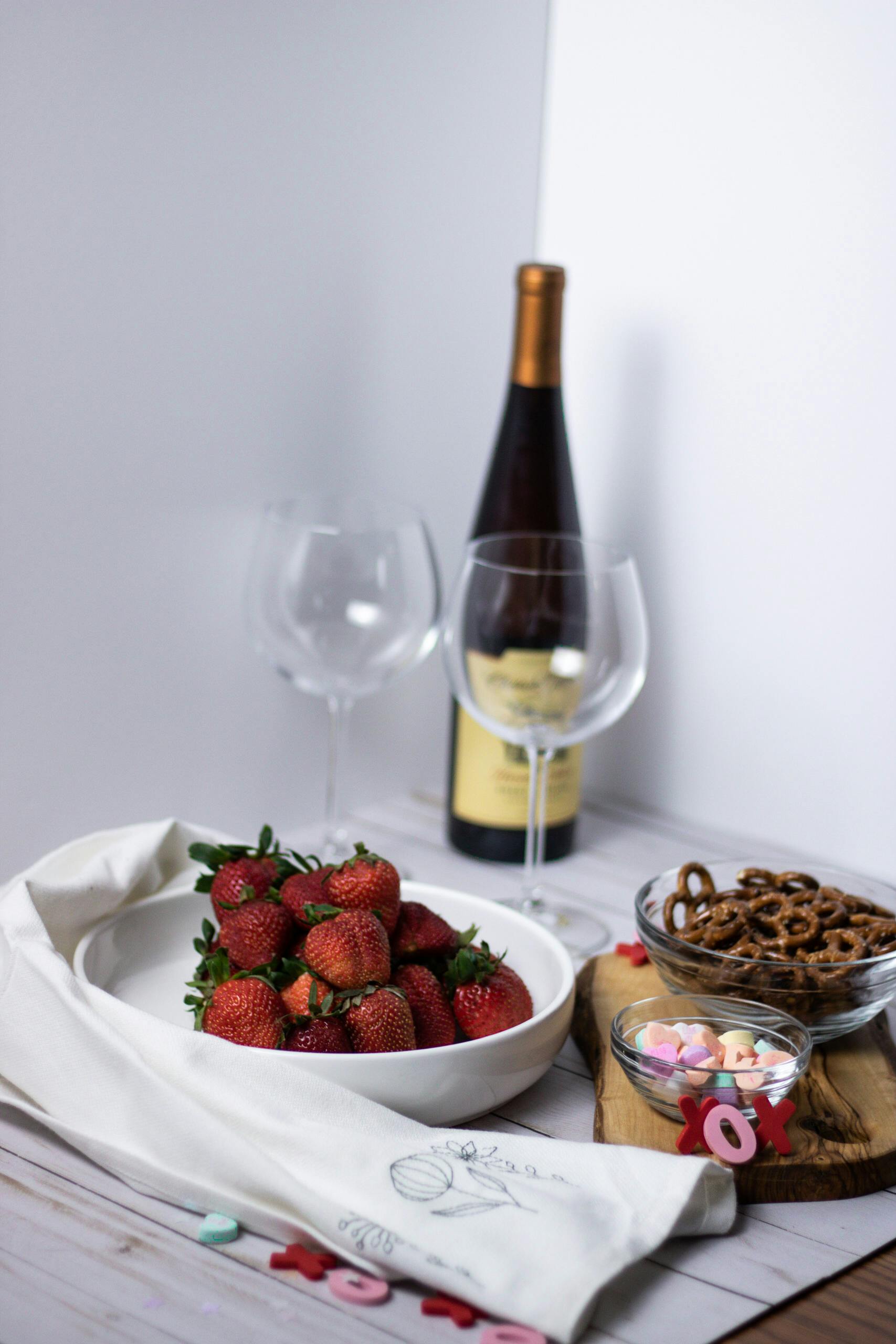 Elegant table setup with strawberries, wine, and pretzels for a delightful romantic atmosphere.