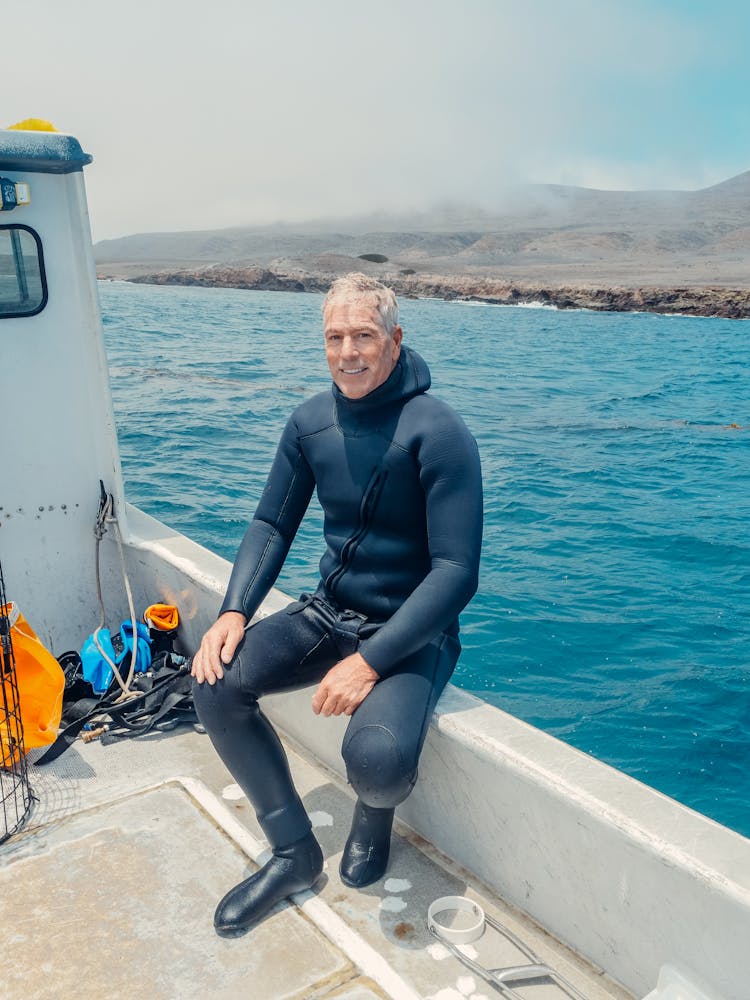 A Man In A Boat Wearing A Scuba Diving Suit