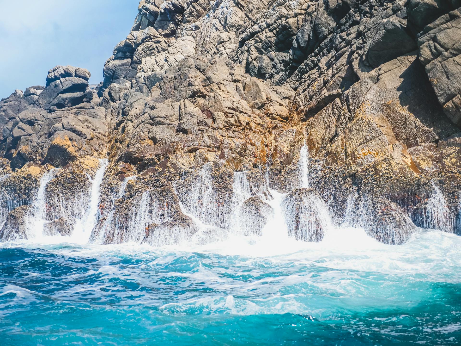 Vivid ocean waves crashing against rugged cliffs with sparkling water and dynamic energy.