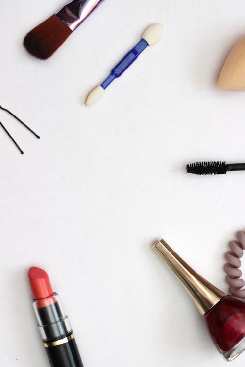 Makeup Products and Accessories Scattered on White Surface 