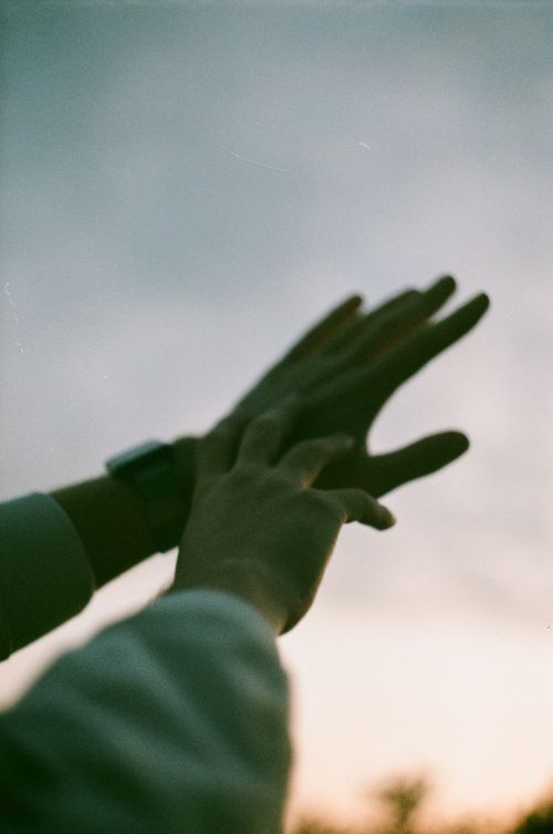 Free Close-up of silhouetted hands reaching into the sky at sunset, conveying unity and aspiration. Stock Photo