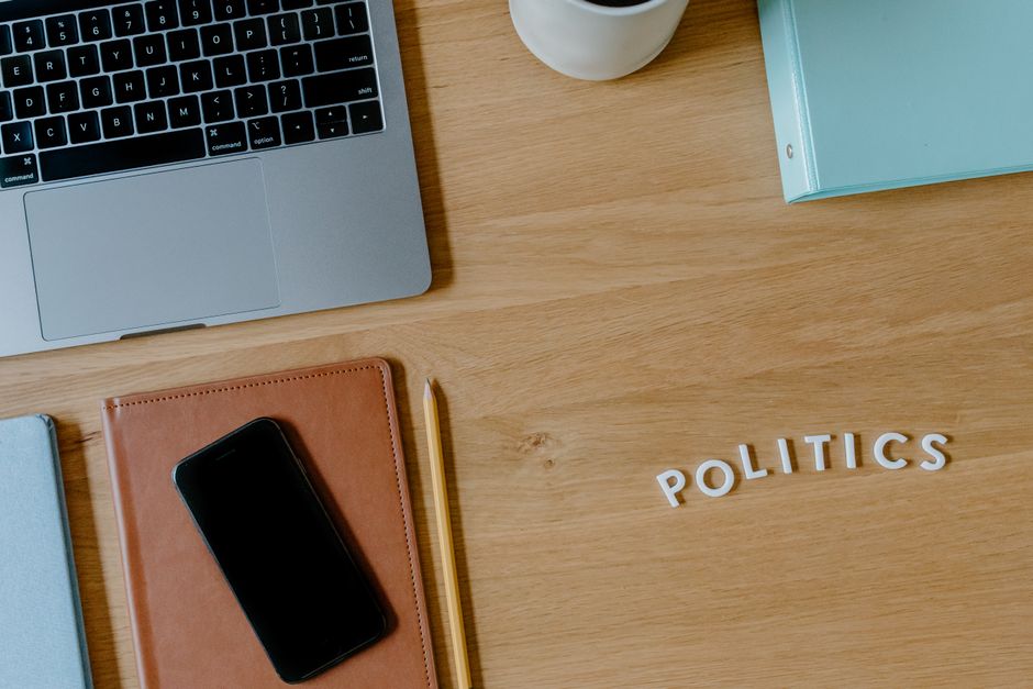 Una vista superior de un espacio de trabajo con un laptop, smartphone y el texto 'políticas' en un escritorio de madera.