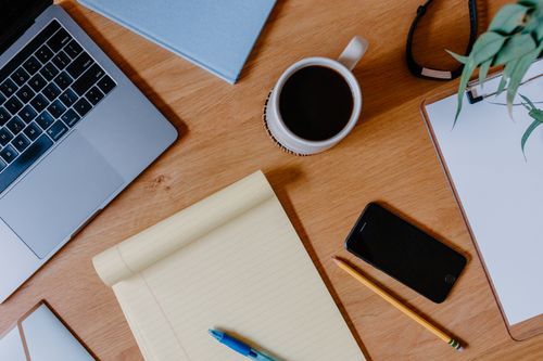 Free A tidy desk featuring a laptop, smartphone, coffee mug, and notepad, ideal for productivity. Stock Photo