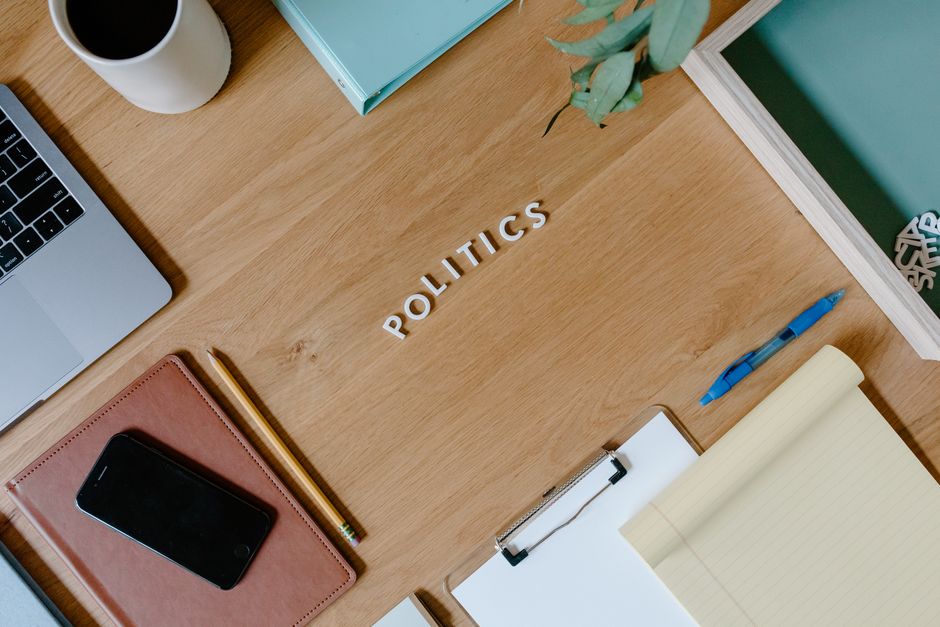Toma aérea de un espacio de trabajo con temática política, que incluye una laptop, planificador y portapapeles.