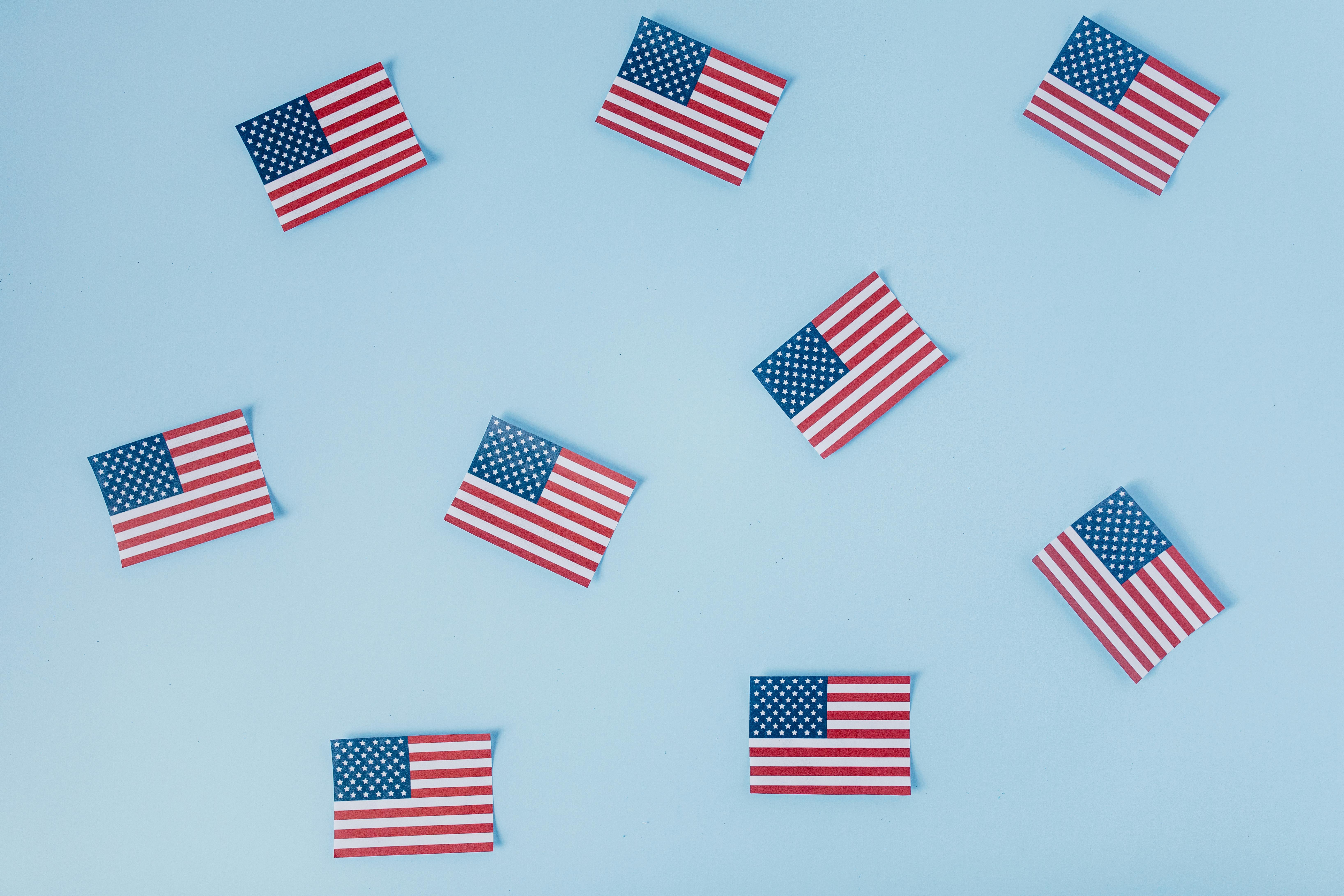 Small American flags laid out on a light blue background. 