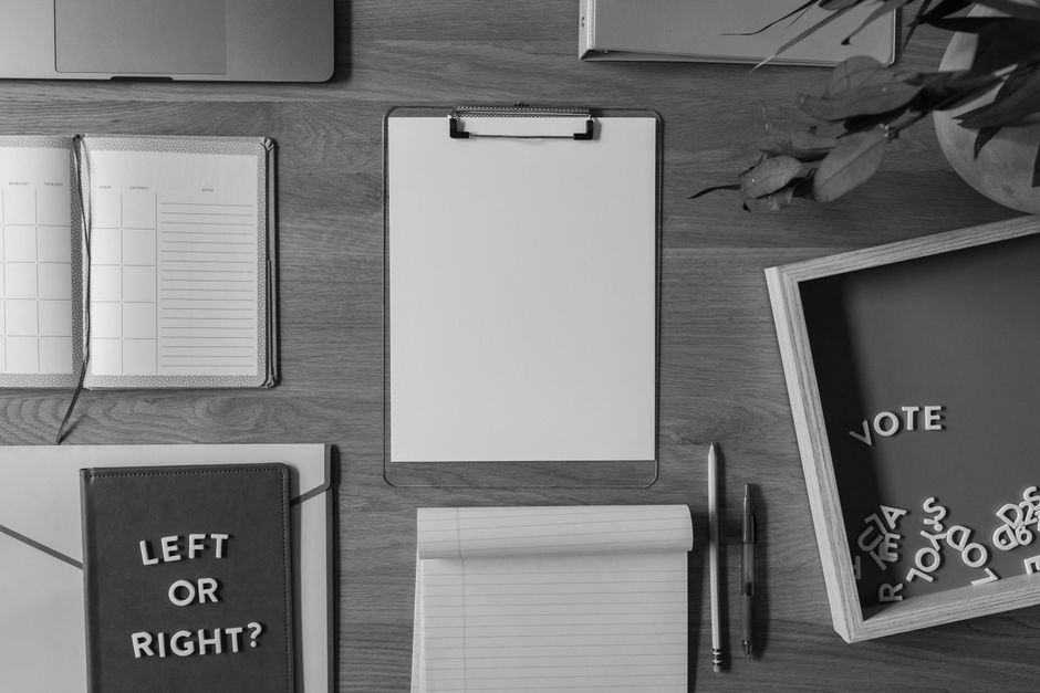Top view of a desk with voting-themed items, including a notepad with 'Left or Right?' and scattered letters spelling 'Vote'.
