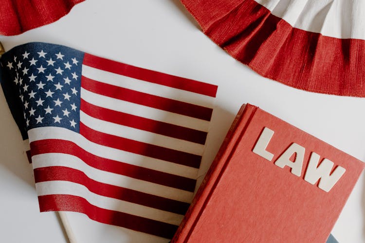 American Flag Beside A Law Book On White Background