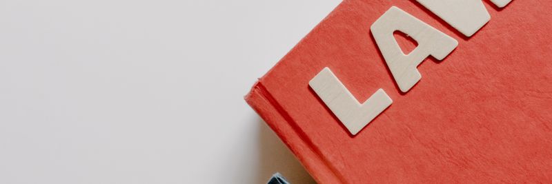 Red law textbook and dark book on white background, symbolizing education.