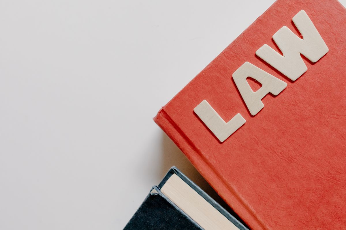 قانون حماية البيانات في مركز دبي المالي رقم 5 لعام 2020 كتاب قانون أحمر بجانب كتاب داكن على خلفية بيضاء