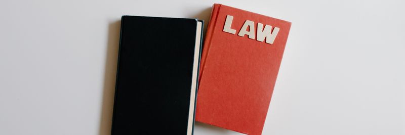 Top view of a law book and black notebook on a white surface, perfect for educational themes.