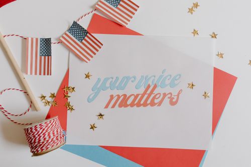 Free Flat lay of 'Your Voice Matters' with American flags and stars on a white background. Stock Photo