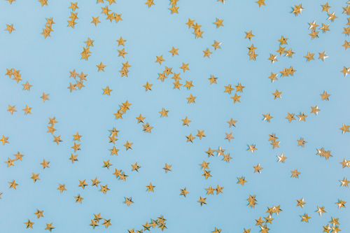 Free Gold star confetti scattered over a light blue surface, perfect for festive occasions. Stock Photo