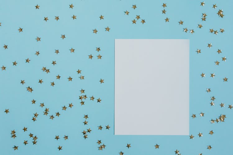 Blank Paper And Confetti Stars On Light Blue Background