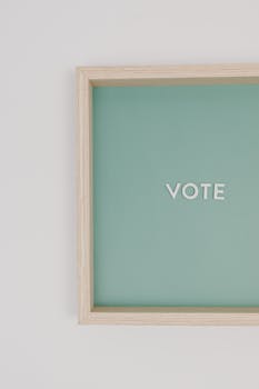 Simple flat lay with vote sign on a green background in a wooden frame.