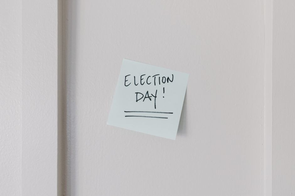Nota adhesiva con el mensaje 'Día de Elecciones' sobre un fondo de pared blanca.