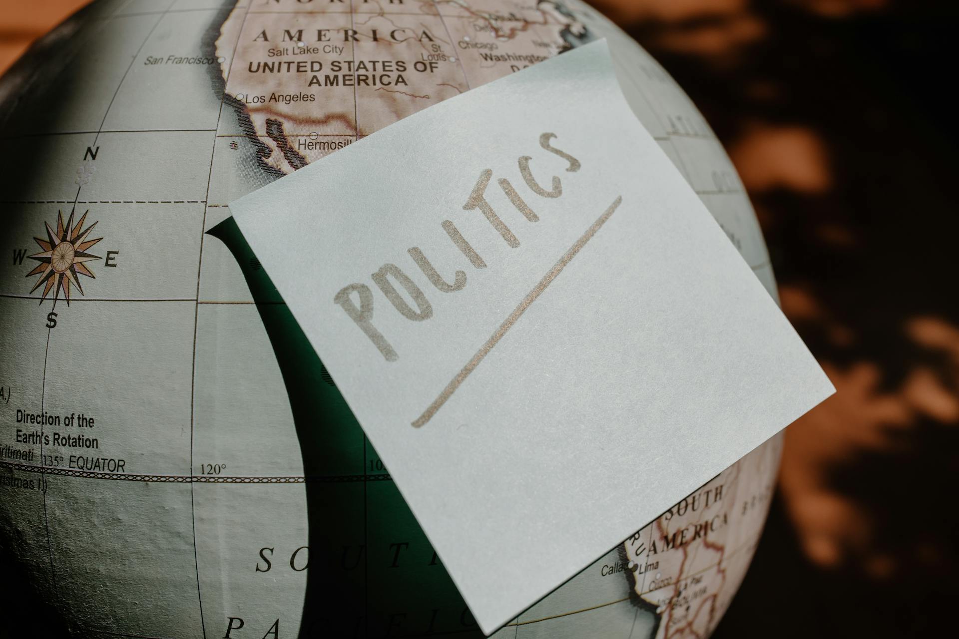 A close-up of a globe with a politics sticky note, symbolizing global political themes.