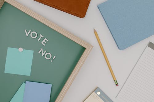 Message on a Wooden Board Near a Pencil and Notebooks