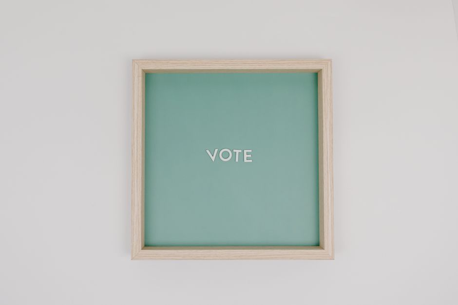 Marco minimalista de madera con texto 'Voto' sobre fondo verde, fondo blanco.