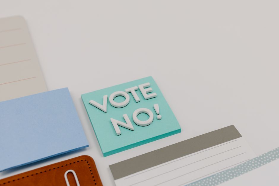 Toma en primer plano de una nota adhesiva con la frase 'Votar No' en un escritorio.