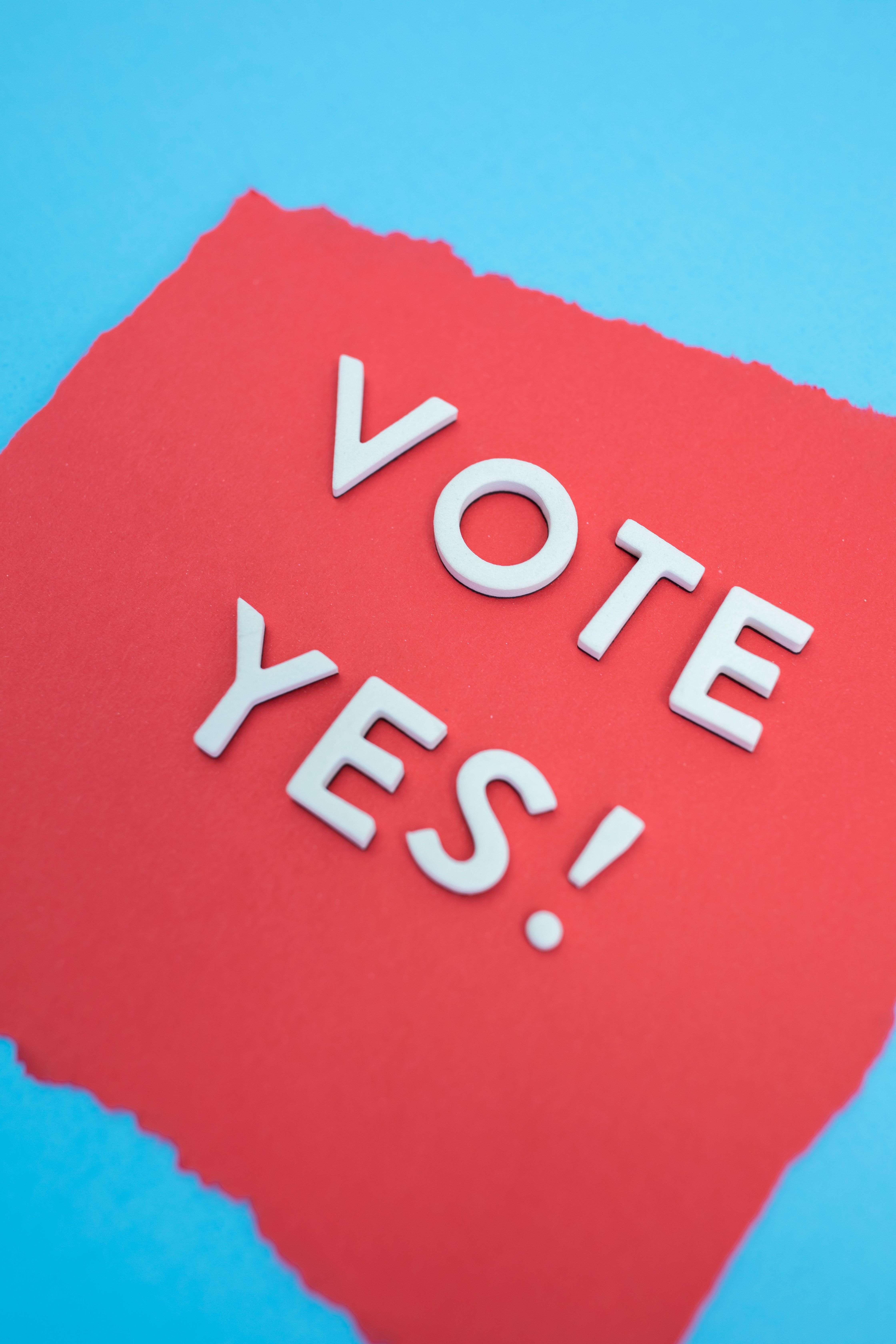 Inspirational 'Vote Yes' message on vibrant red and blue paper background, promoting positive engagement.