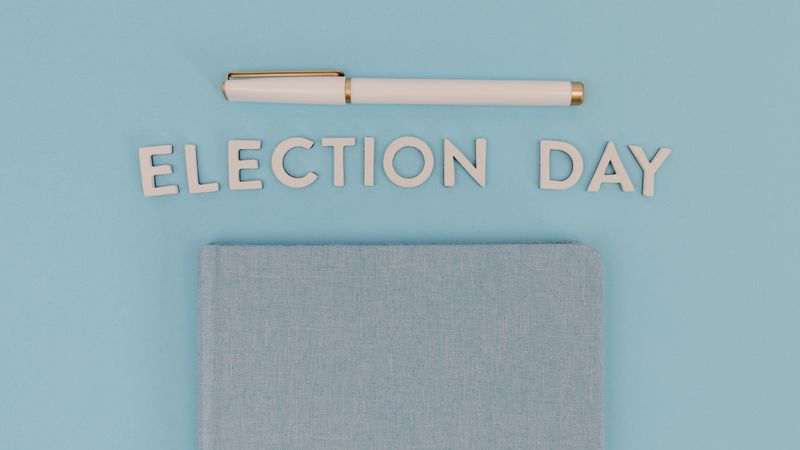 Blue notebook and pen against a light blue background reading 'Election Day', ideal for campaign themes.