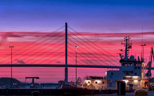 Silhouette of a Bridge Under Red Clouds and Blue Sky Taken during Night Time