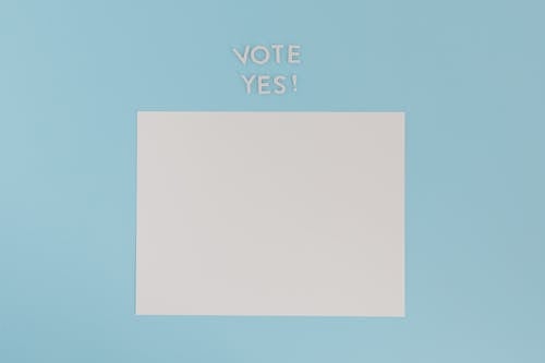 Free A Blank White Paper with a Vote Yes Text on a Blue Background Stock Photo