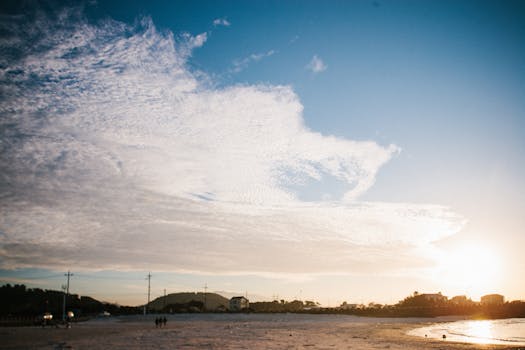 Captivating beach view with expansive clouds and setting sun, perfect for serene moments.