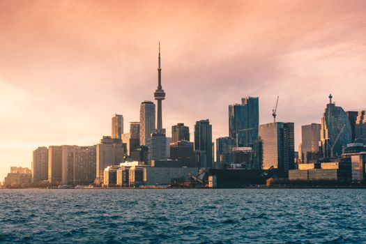 Breathtaking view of Toronto's skyline with CN Tower at sunset over Lake Ontario.
