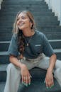 Woman in Gray Crew Neck T-shirt and Gray Pants Sitting on Gray Concrete Stairs