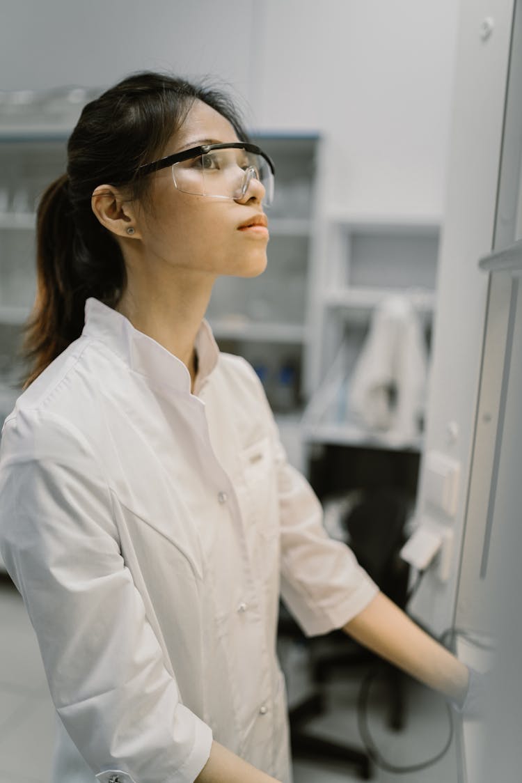 A Woman In White Lab Coat Wearing An Eyeglasses