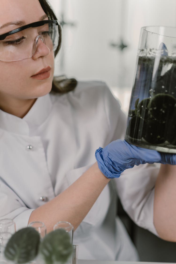 A Woman Looking At A Beaker With Liquid