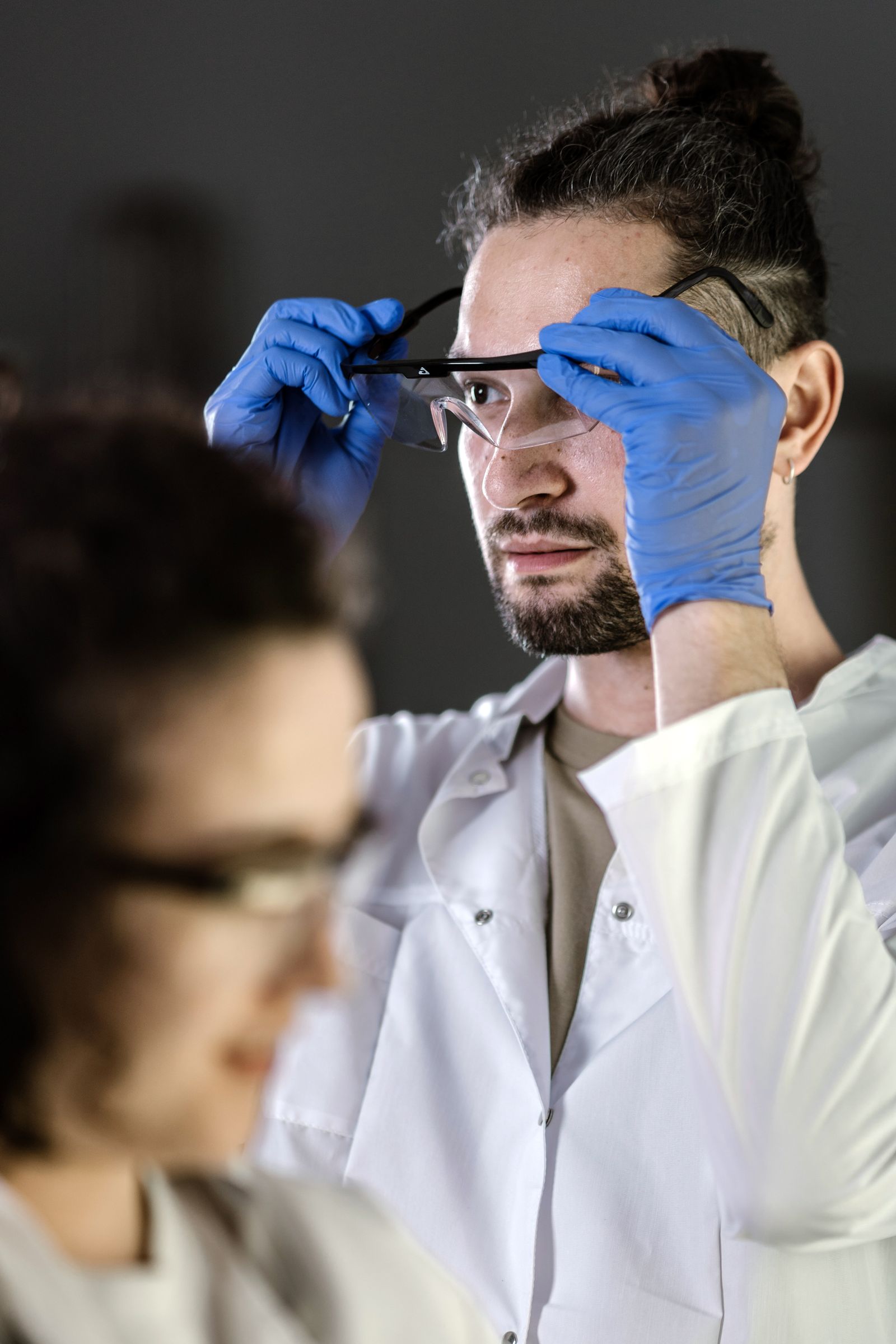 Worker adjusting safety goggles while wearing blue protective gloves