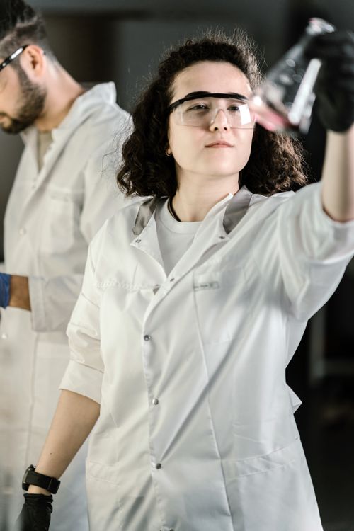 Free Young female scientist examining a beaker in a laboratory setting. Stock Photo