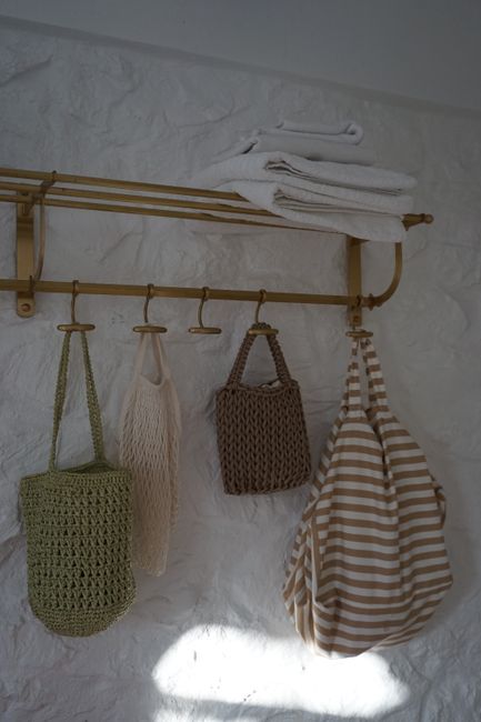 A serene home interior featuring woven bags and folded towels on a wall rack, creating a minimalist decor.